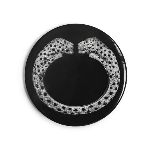 A simple circular pocket mirror, black with Cartier's diamond twin-headed panther bangle in the centre
